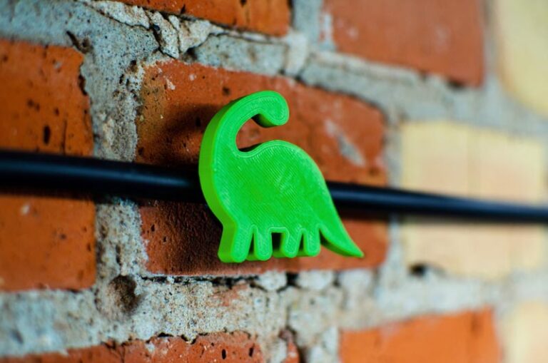 Zdjęcie wydrukowanego uchwytu na kabel w kształcie dinozaura
